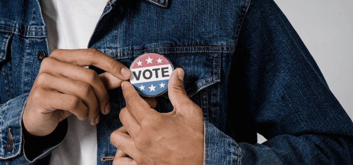 Person pinning "vote" button to jacket