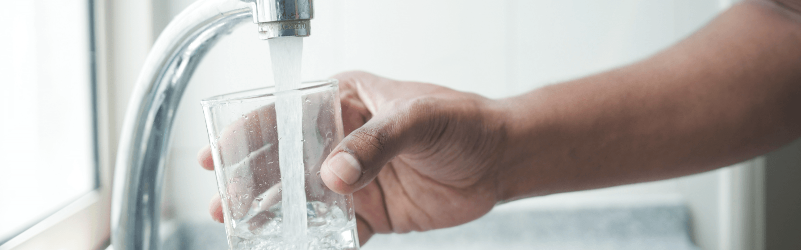 Person filling glass from faucet